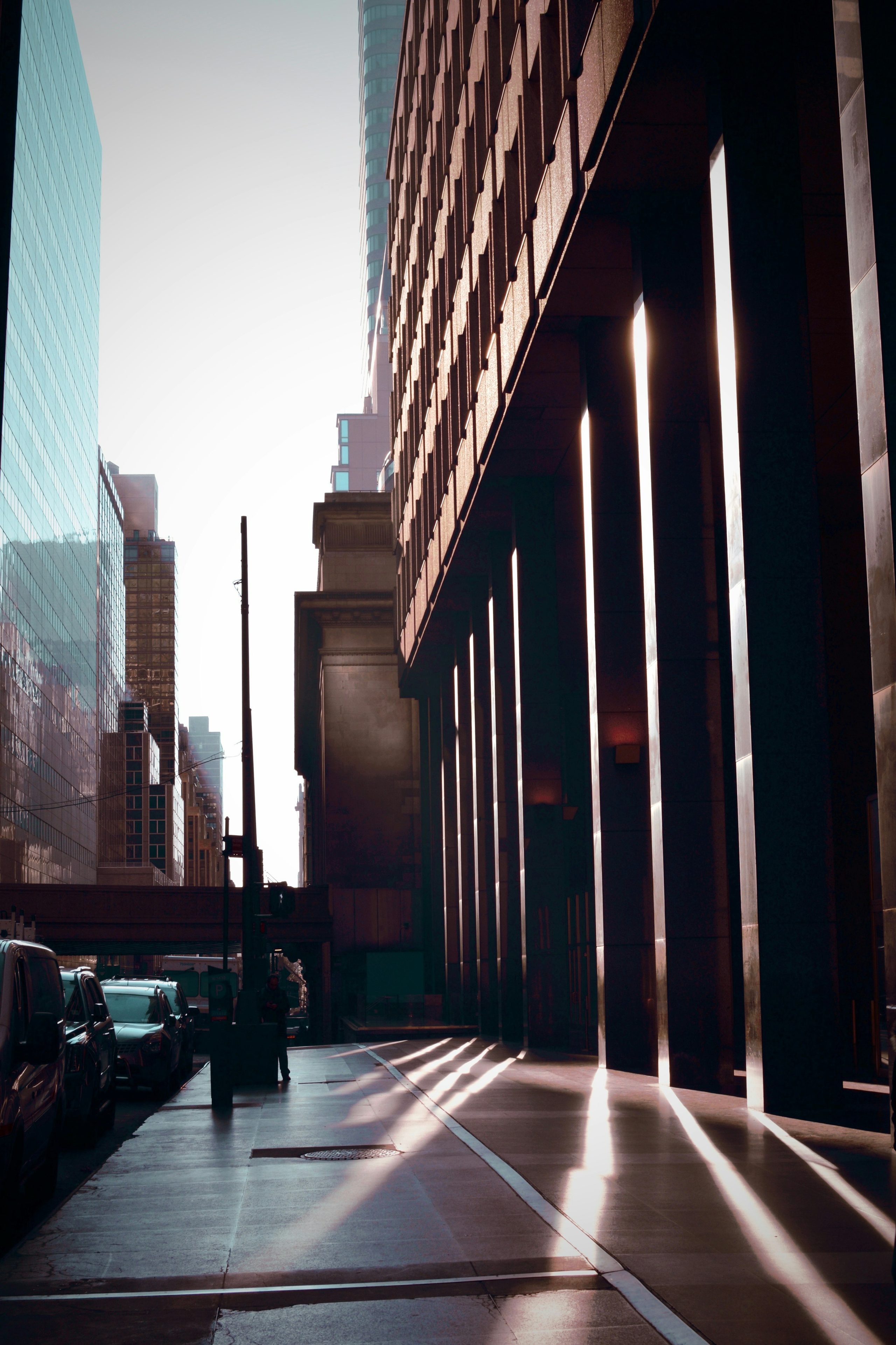A bright line of sun reaches between glass and brick buildings.